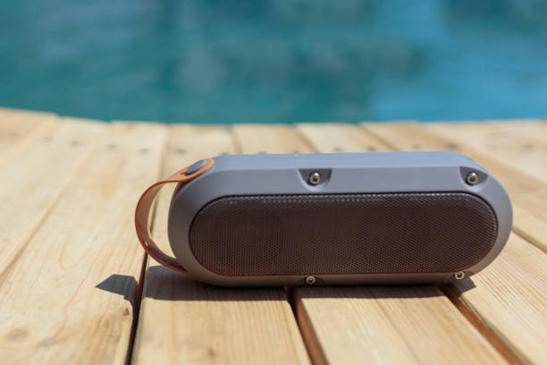 Portable Bluetooth speaker sitting on a wooden deck, perfect for outdoor listening by the pool.