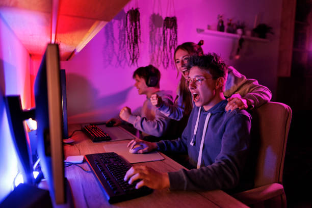 Three friends excitedly gaming together on monitors in a dimly lit, colorful room.